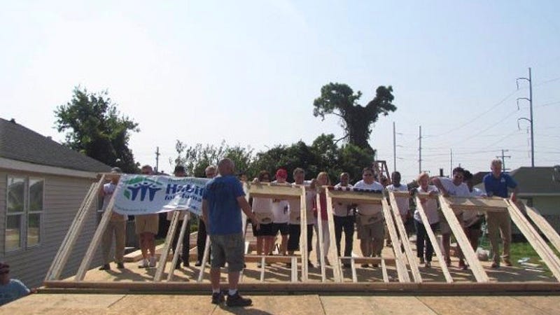 Volunteers raising a wall frame at a Habitat for Humanity build